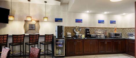 Una cocina moderna con comedor, equipada con cafetera, microondas y televisor de pantalla plana.