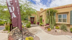Un bâtiment avec une porte rouge, des cactus et un drapeau portant l’inscription « VEDA ».