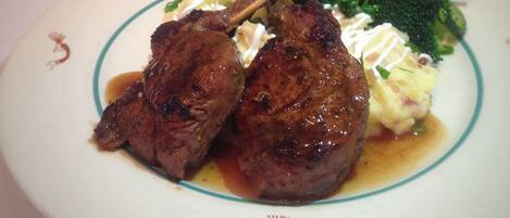 A plate of food with two lamb chops, broccoli, and mashed potatoes.