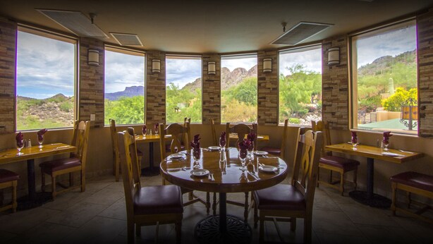 Un espace repas avec une grande table ronde et des chaises, de grandes fenêtres offrant une vue sur un paysage montagneux.
