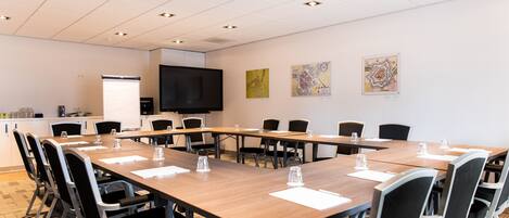 A conference room with a long table, chairs, a TV, and artwork on the walls.