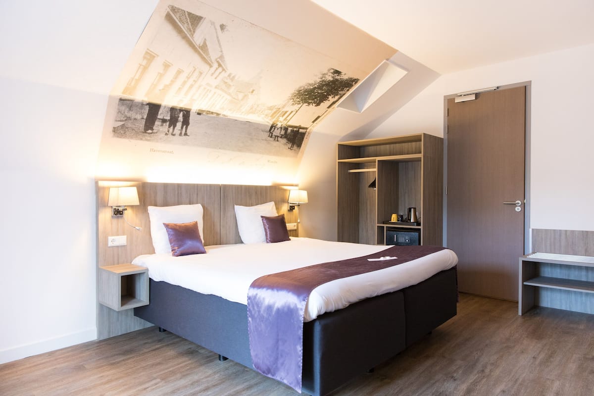 Une chambre d’hôtel moderne dotée d’un grand lit, d’une armoire intégrée et d’une fresque peinte au plafond.