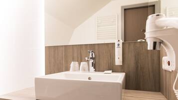 A modern bathroom with a rectangular sink, a mirror, and a hairdryer mounted on the wall.