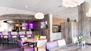 Un restaurante moderno con barra, detalles de madera e iluminación morada.