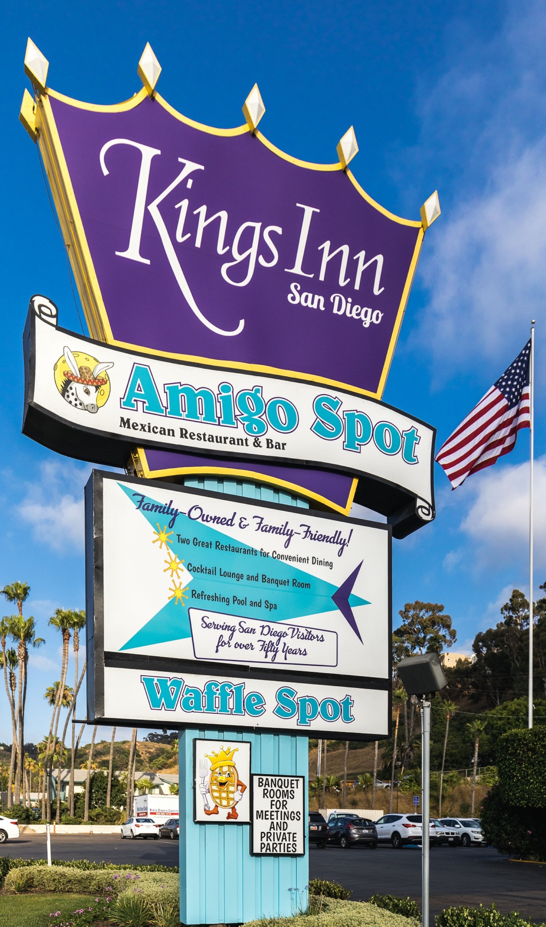 Een Kings Inn bord met een paarse banner en een wit bord eronder waarop Amigos Spot staat, een Mexicaans restaurant en bar.