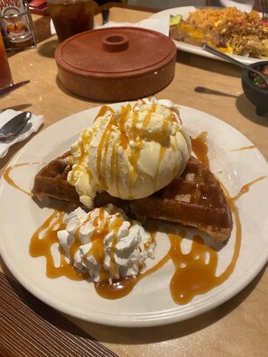 A dessert plate with ice cream, whipped cream, and caramel sauce. - Kings Inn San Diego (San Diego)