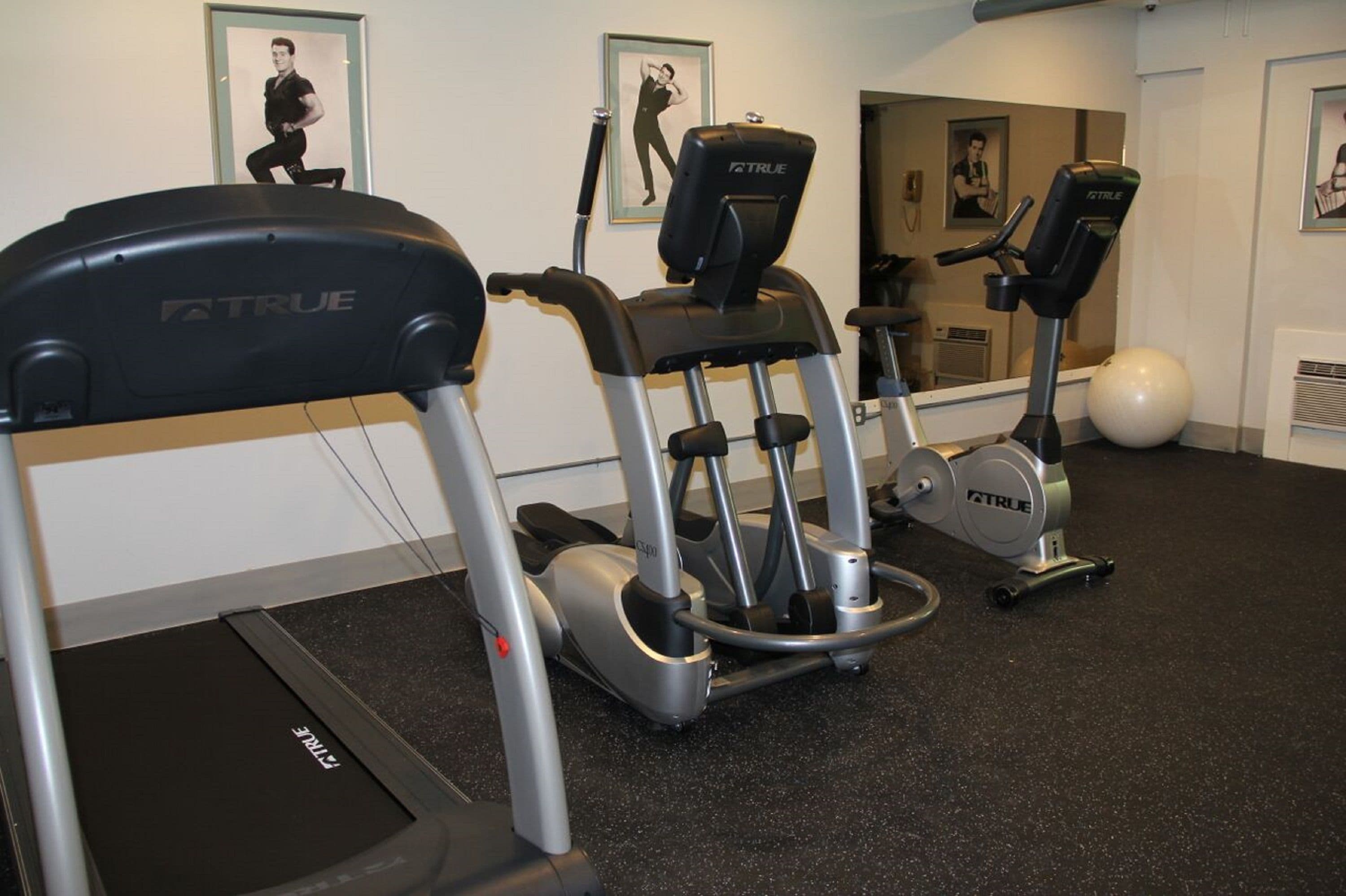 A gym with treadmills and elliptical machines, a large exercise ball, and motivational posters on the wall.