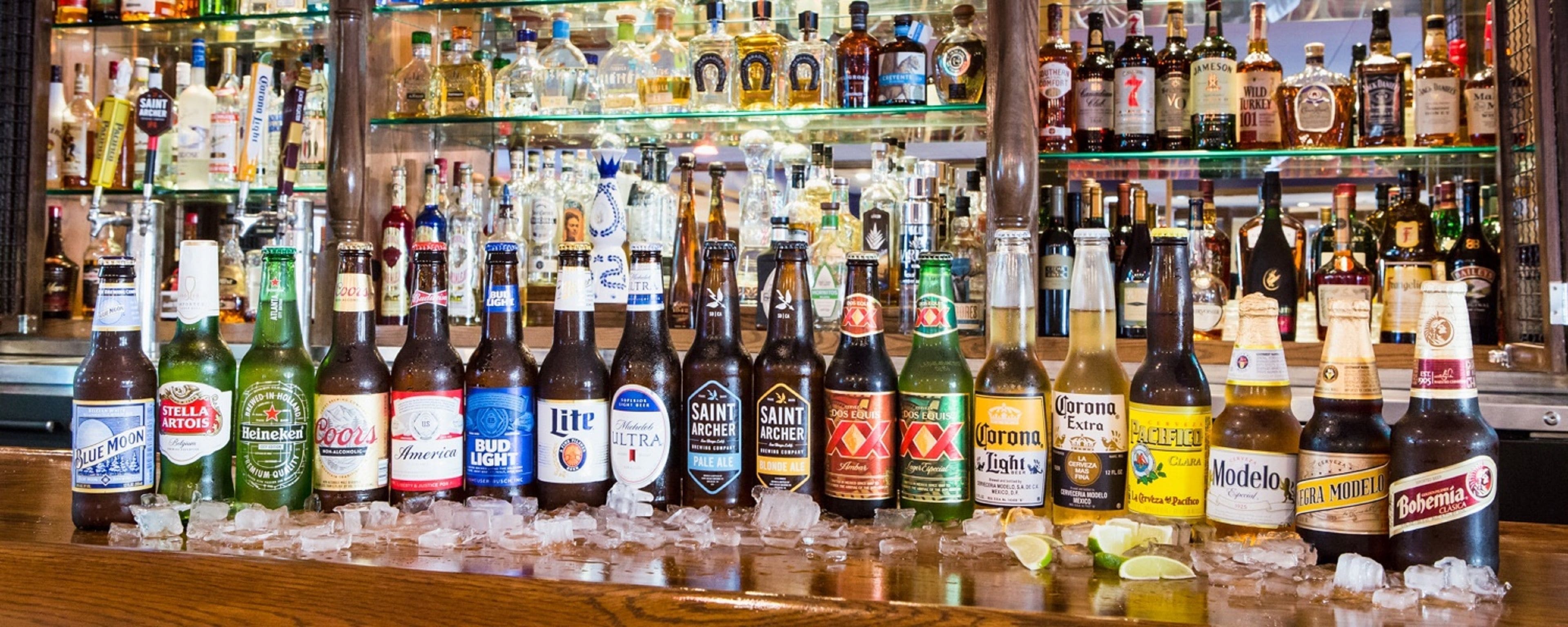Un bar con una variedad de botellas de licores exhibidas en estantes y hielo.