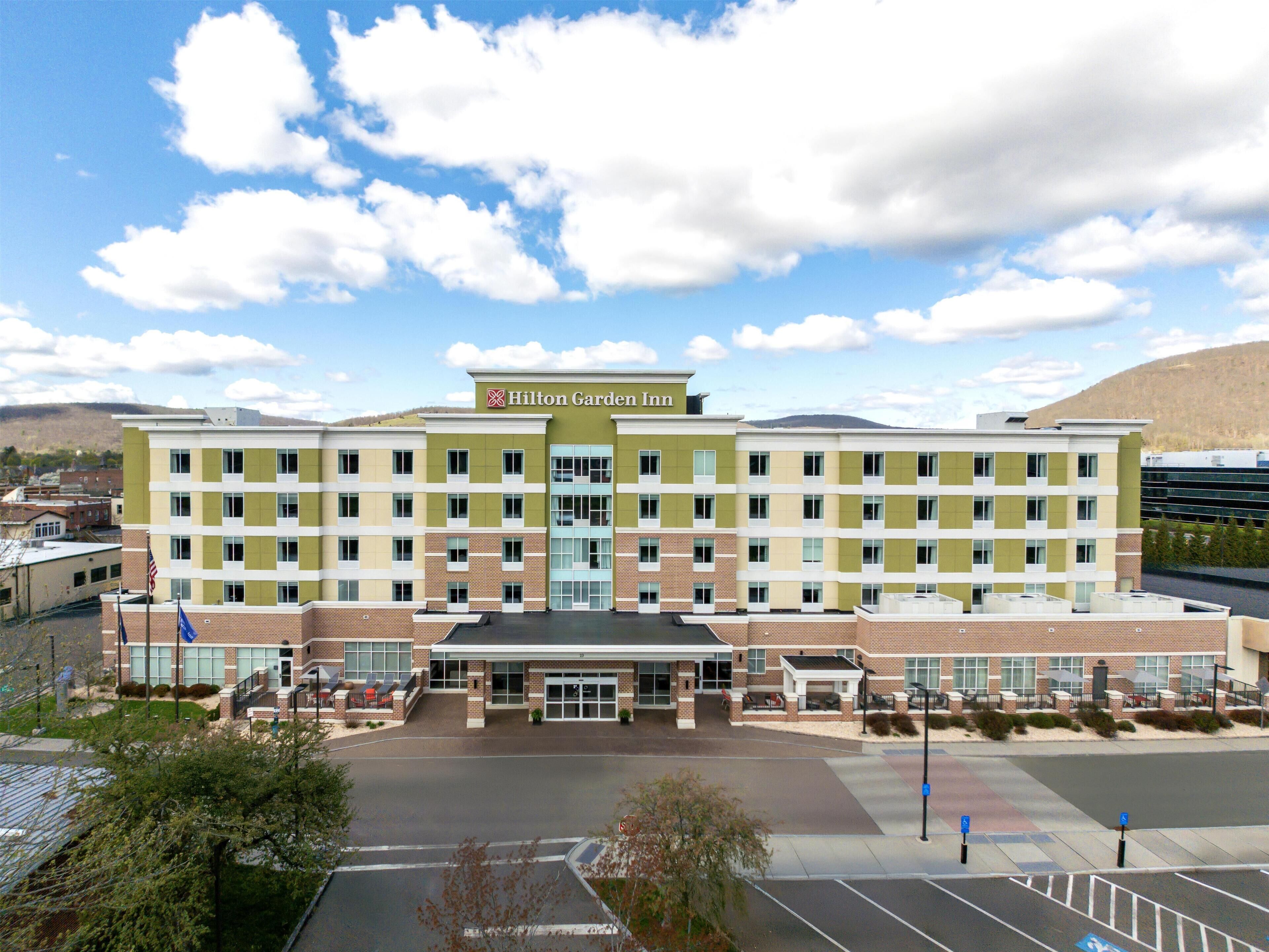 A multi-story Hilton Garden Inn with a brick facade, large windows, and a parking lot.