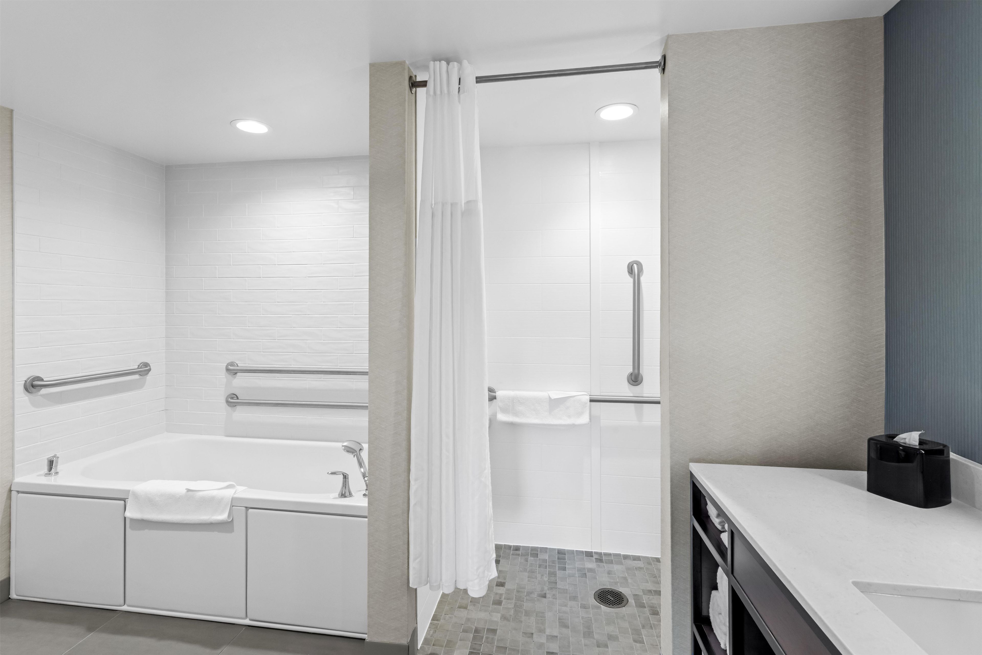 Un baño moderno con bañera, ducha y barras de apoyo.