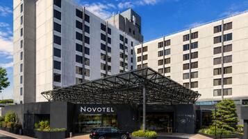 Un hotel con fachada moderna, un acceso cubierto y un área de estacionamiento.