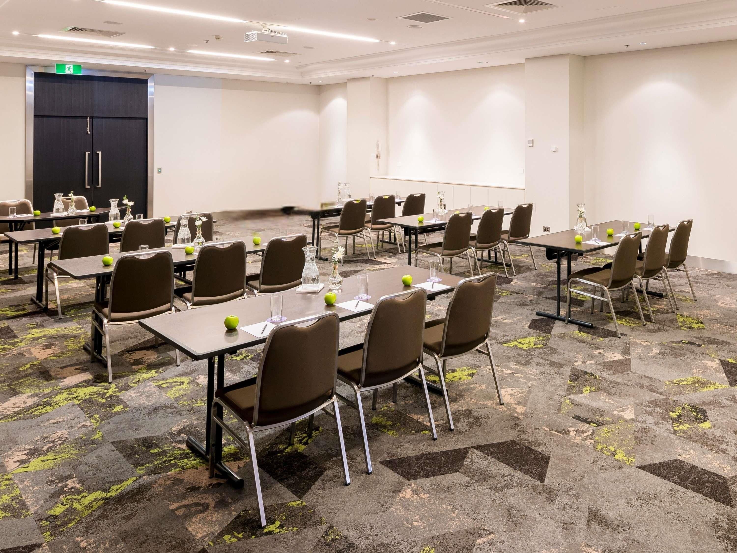 A conference room with multiple tables and chairs, equipped with nameplates and apple slices.