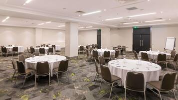 A conference room with multiple round tables, chairs, and a whiteboard.