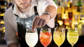 A bartender preparing drinks at a bar with various bottles in the background.