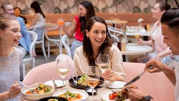 A group of people dining at a restaurant with various dishes and drinks on the table.