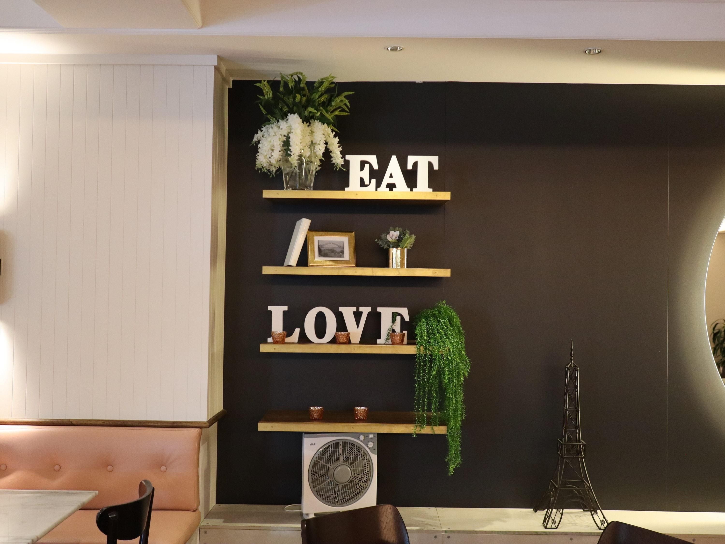 Une pièce avec un mur noir, des étagères en bois et un ventilateur.