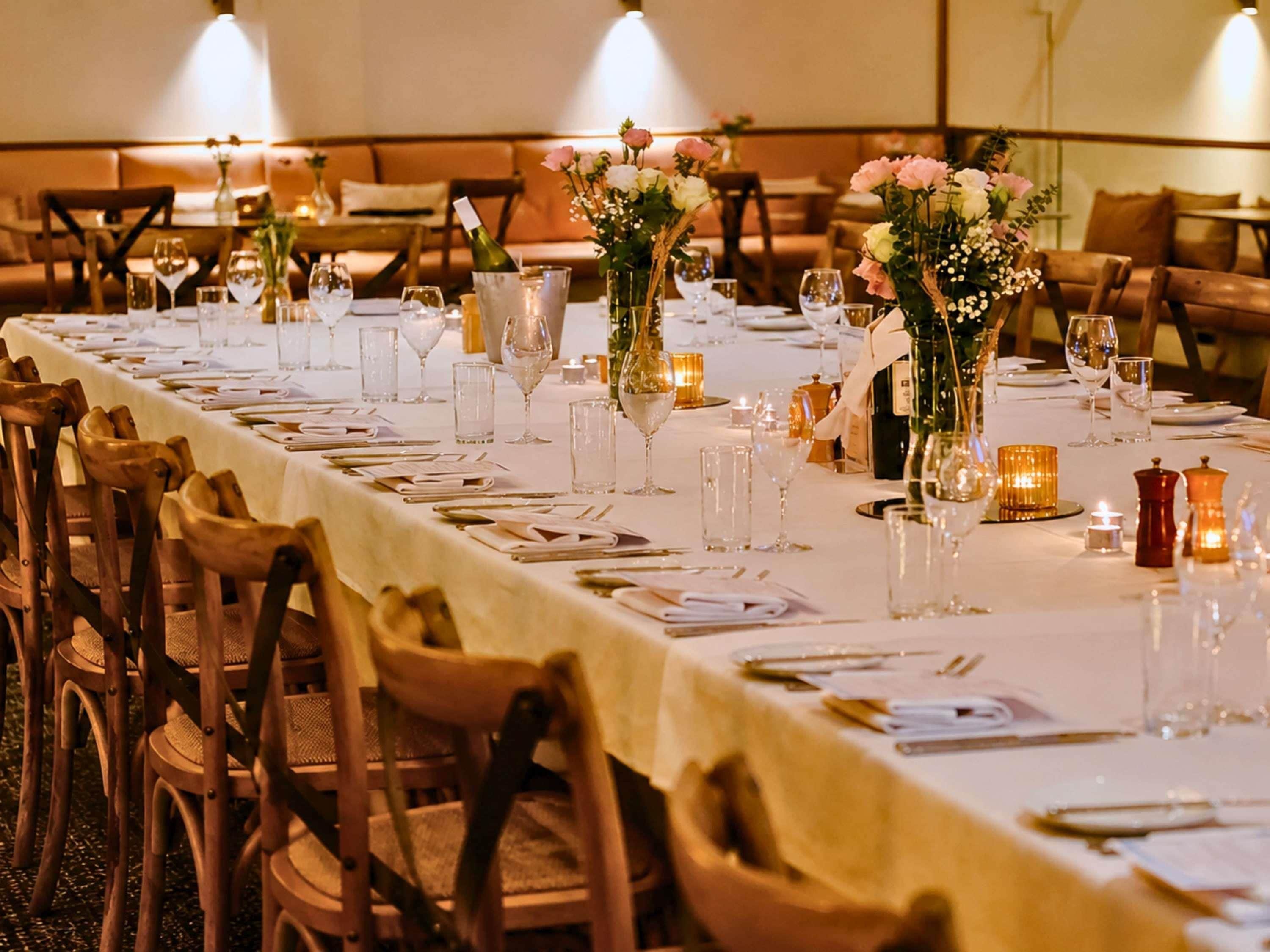 A long dining table set with chairs, candles, and floral centerpieces.