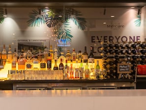 A bar area with various liquor bottles and glasses, a sign for mulled wine, and a wall with 'Mercure Hotels' and 'Everyone' branding. - Novotel Sydney International Airport Hotel (Wolli Creek)