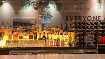 A bar area with various liquor bottles and glasses, a sign for mulled wine, and a wall with 'Mercure Hotels' and 'Everyone' branding.