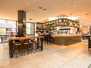 A modern bar area with a curved counter, seating, and a variety of bottles and glasses on shelves.