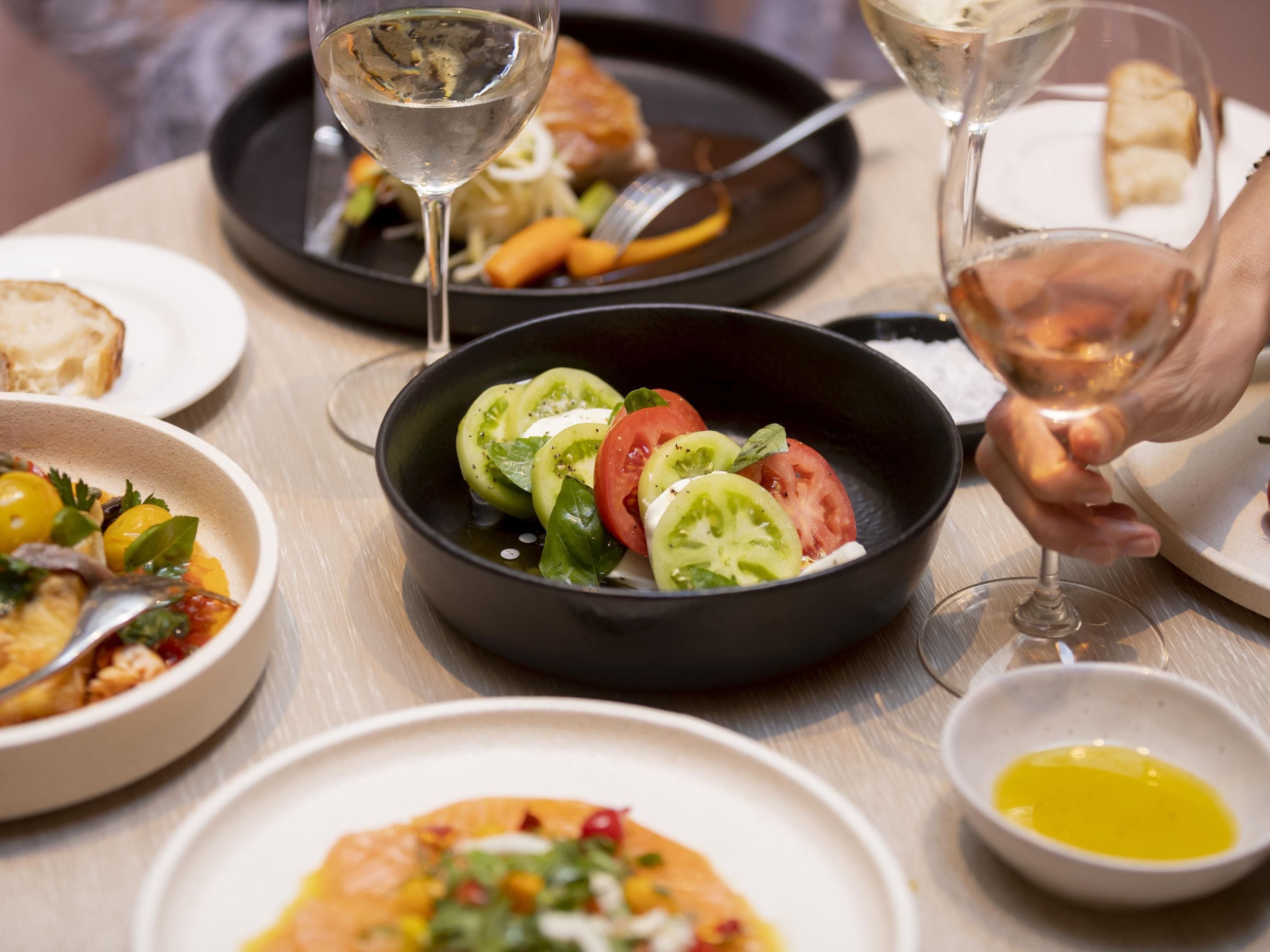 A dining table with various dishes, including a salad in a black pan, a bowl of soup, and plates with bread.
