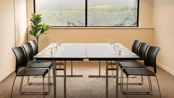 A conference room with a long table, black chairs, and a potted plant.