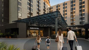 Entrada de hotel con diseño moderno, un letrero de Novotel y una marquesina.