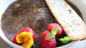 A bowl of chocolate pudding with strawberries and a slice of bread.