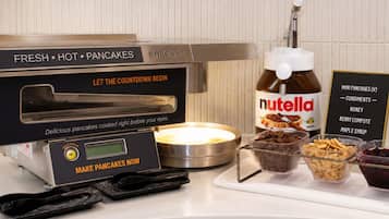 A self-service pancake station with a Nutella dispenser and condiments.