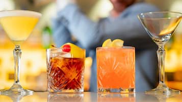 Three different types of drinks in martini glasses on a bar counter.