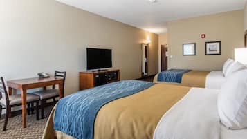 Ett hotellrum med två sängar, ett skrivbord med en stol, en tv och en minibar.
