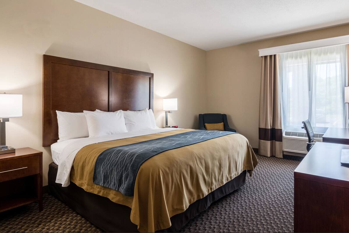 Une chambre d’hôtel avec un grand lit, deux tables de chevet, un bureau et une chaise.