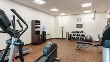 A gym with exercise equipment, a water dispenser, and a clock on the wall.