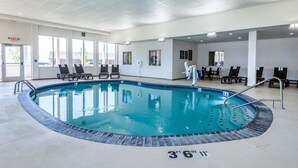 Een binnenzwembad met helder water, omringd door ligbedden en een betegeld zonnedek.