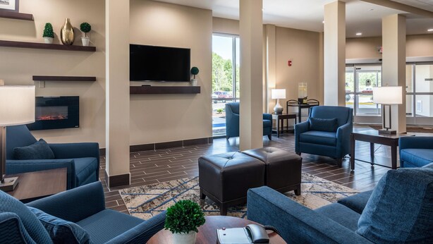 Een hotellobby met blauwe zitplaatsen, een flatscreen televisie en een open haard.
