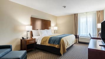 A hotel room with a bed, bedside tables, a desk, a chair, and a window with curtains.