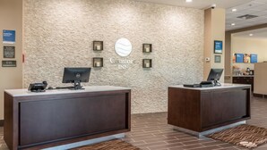 Een receptiegedeelte met twee donkerhouten balies, een muur met een stenen textuur, en een bord waarop 'Comfort INN' staat.