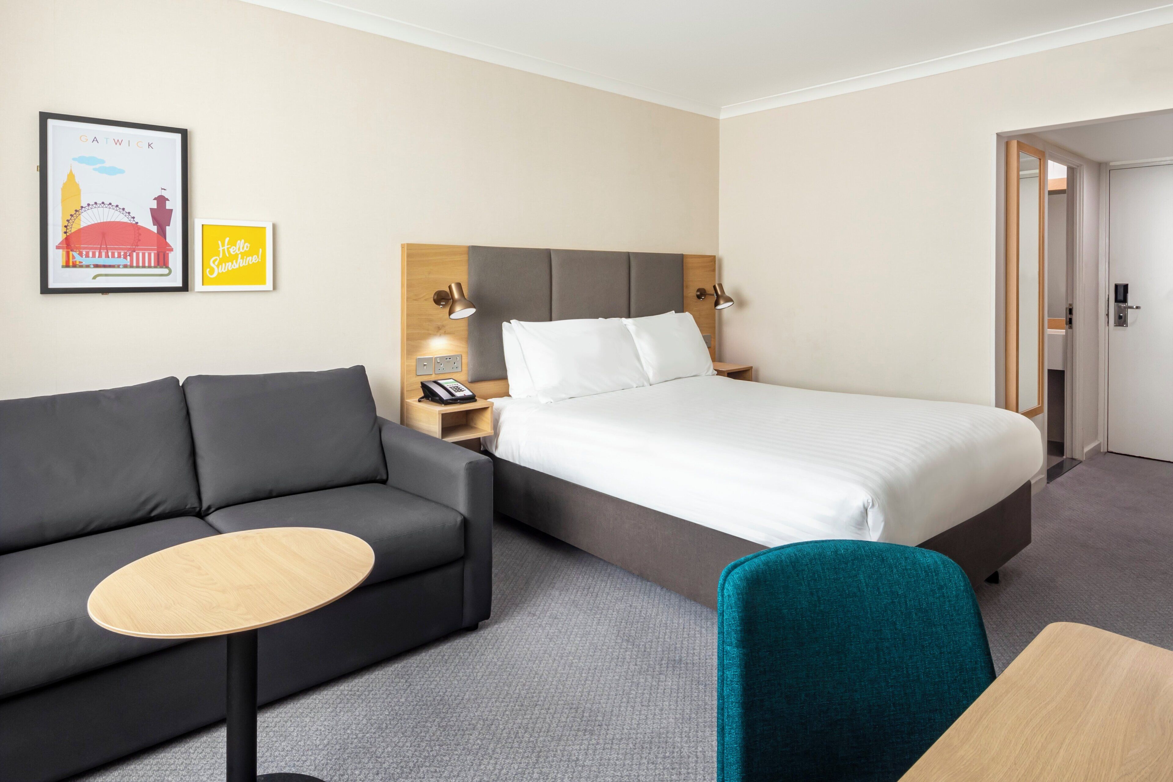 Una habitación de hotel con una cama, un sofá, una mesita y dos lámparas de pared.