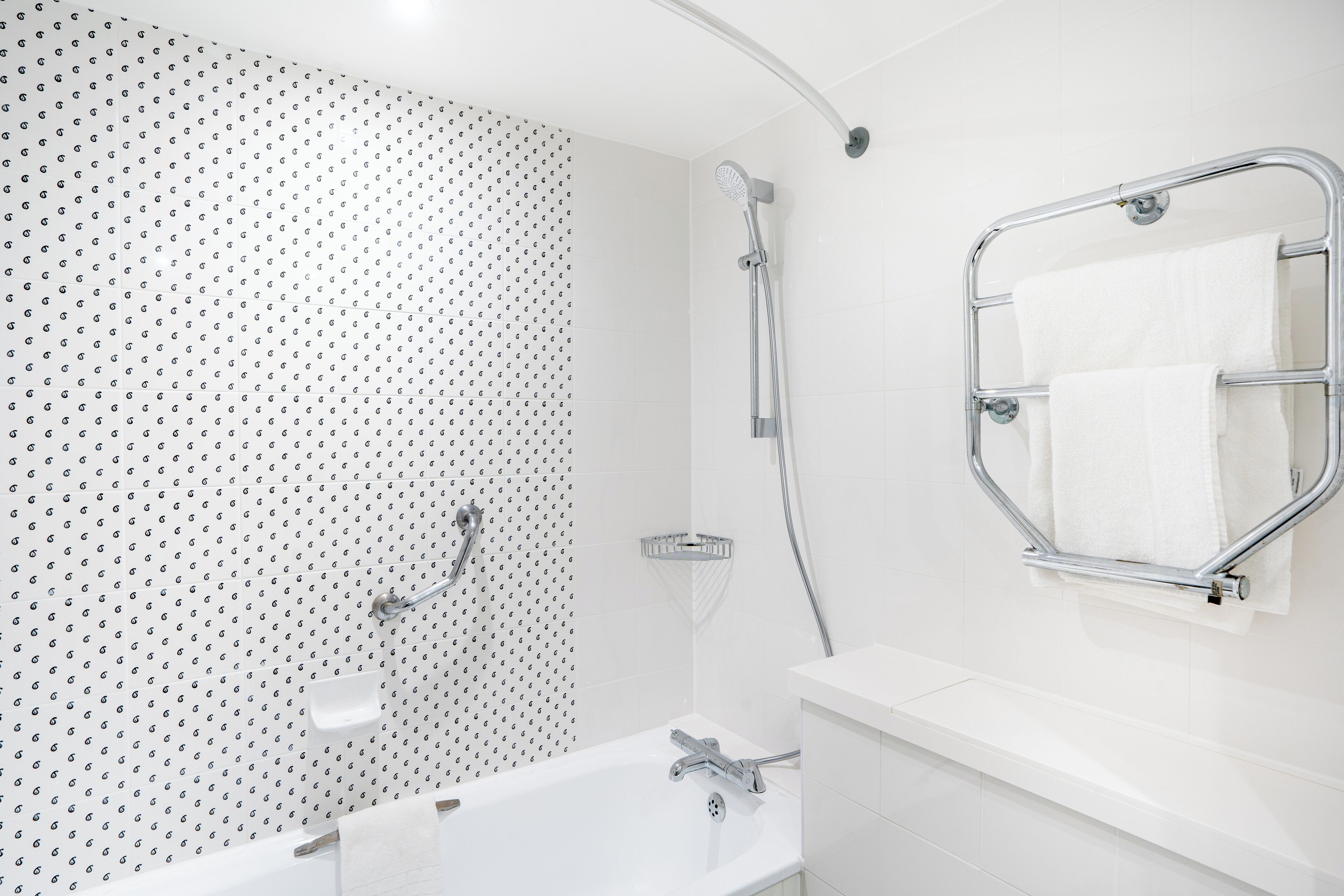 A modern bathroom with a white sink, chrome fixtures, and a shower with a handheld showerhead.