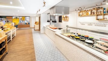 Una cocina moderna con mesas de buffet, mostrando una variedad de alimentos y un cartel que dice "EAT FAB FOODS".
