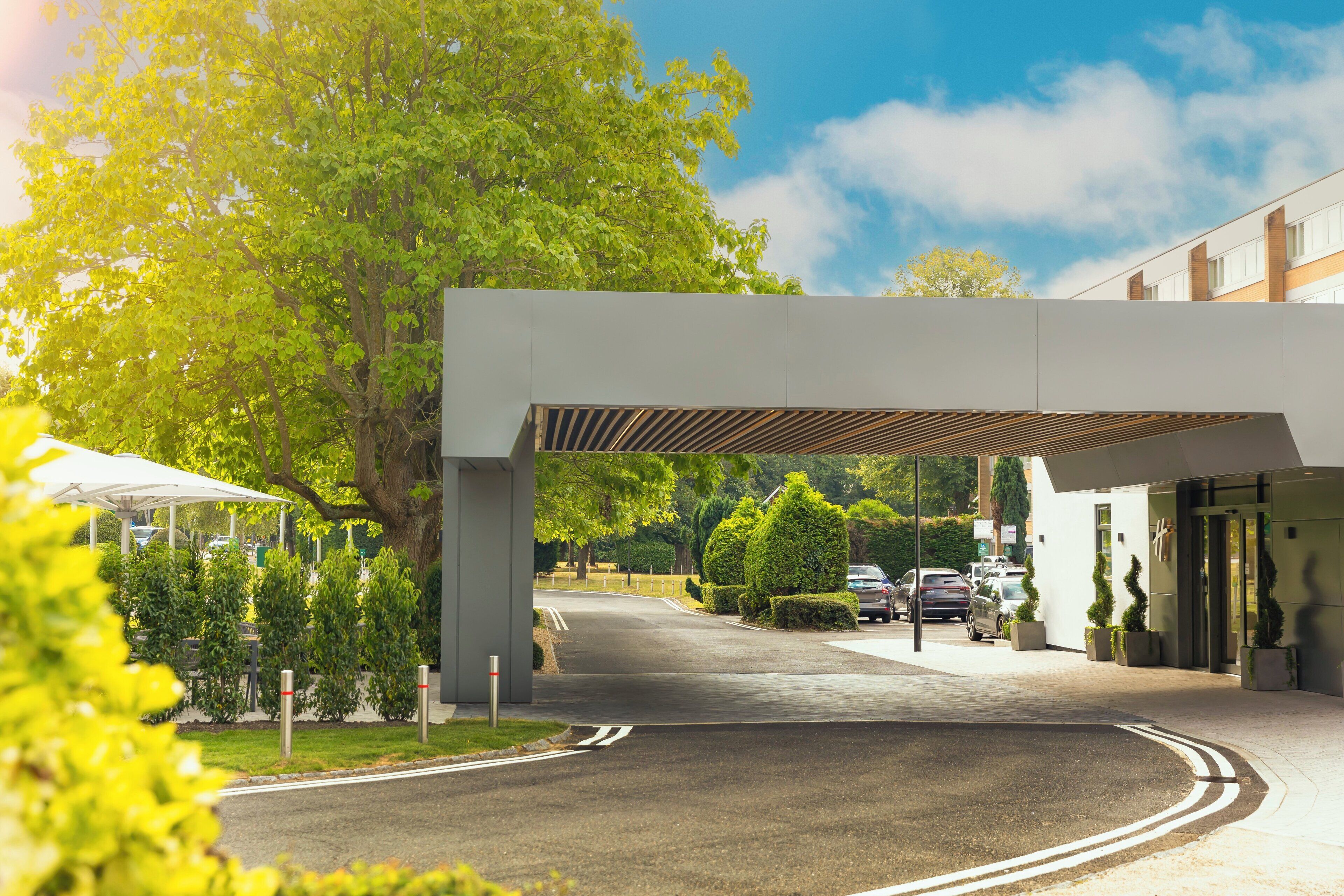A modern building with a covered entrance and a parking area.