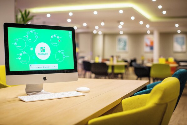 Un ordinateur de bureau doté d’un écran vert affichant un schéma de réseau, posé sur un bureau en bois dans un bureau moderne.