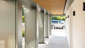 A modern building with a covered walkway, large glass doors, and a parking area visible in the background. - Holiday Inn London-Gatwick Airport by IHG (Horley)