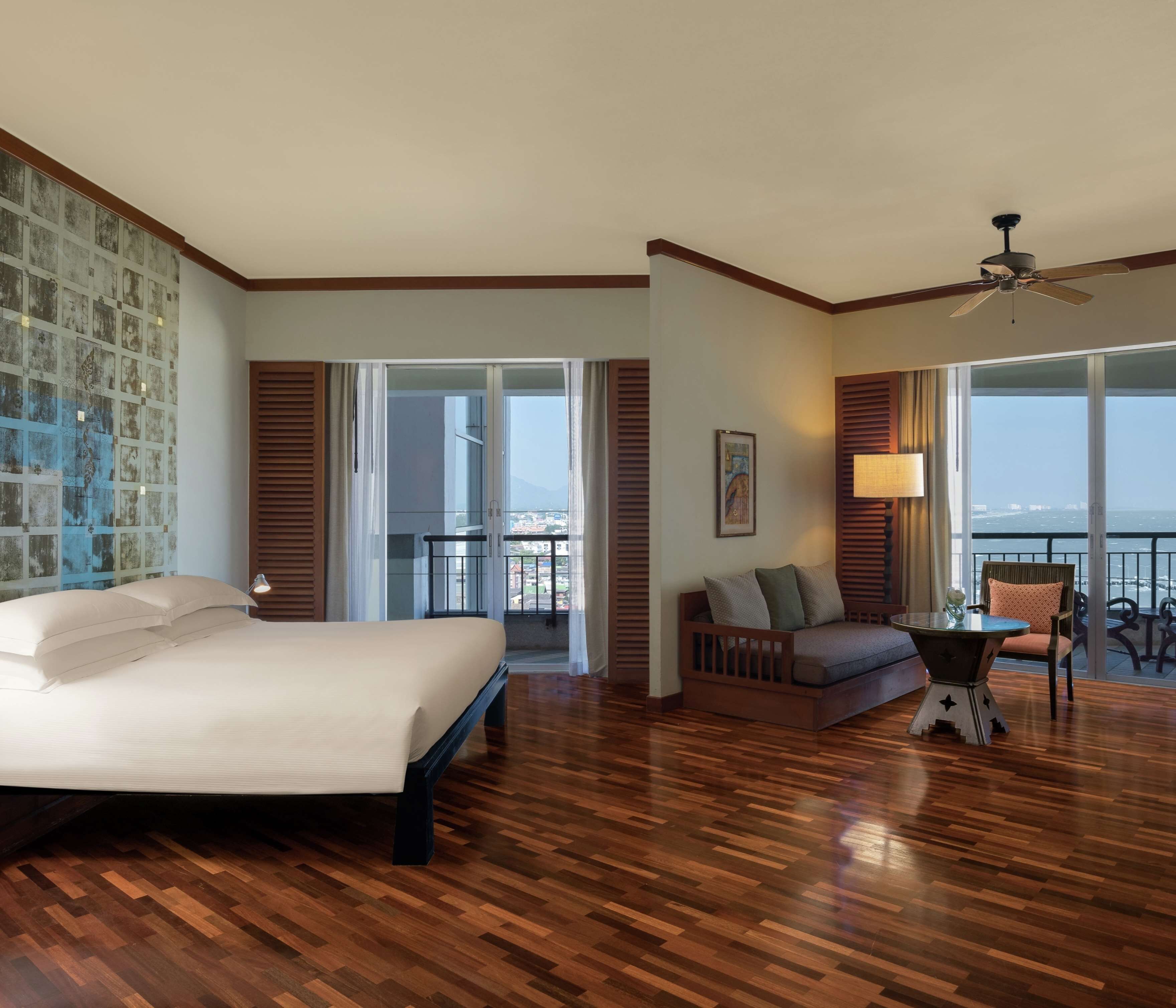 Une chambre d’hôtel avec un grand lit, un canapé, une petite table et un balcon avec vue.