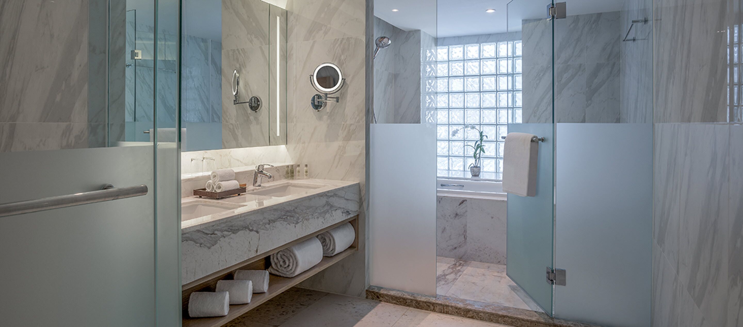 A modern bathroom with a marble sink, glass shower enclosure, and a large mirror.
