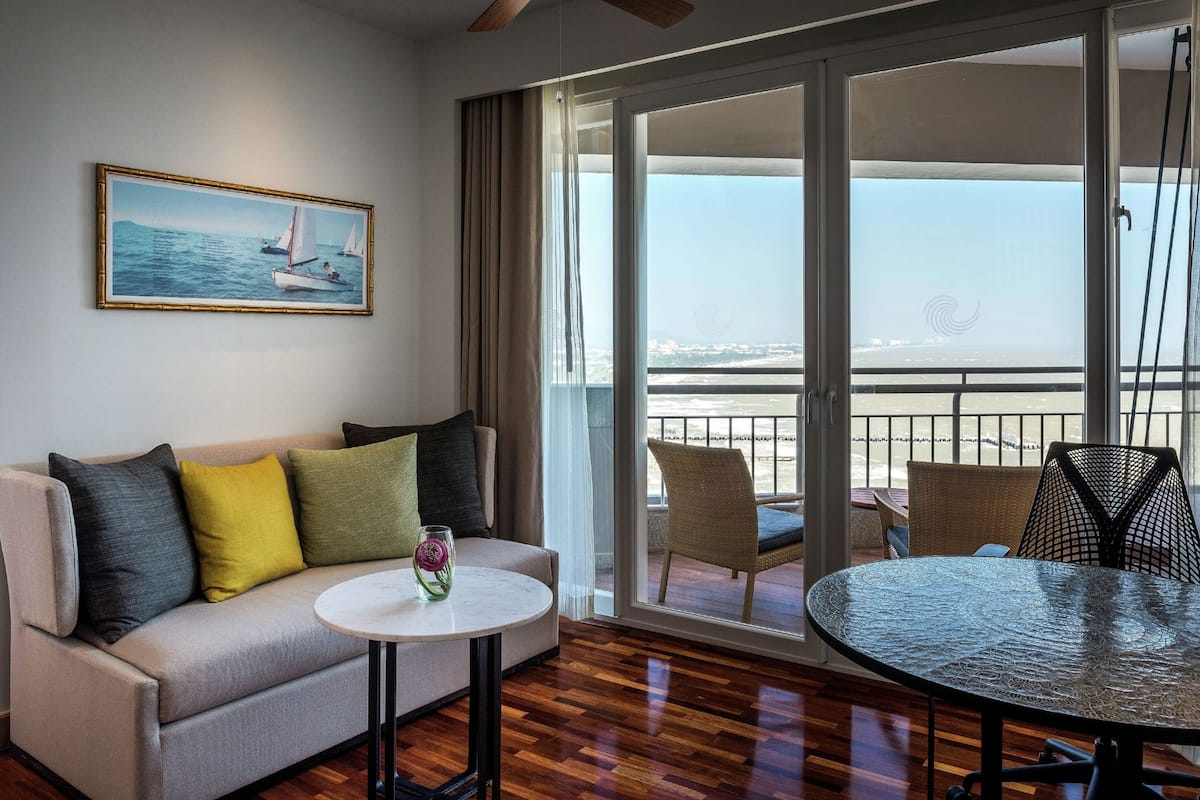 Een moderne woonkamer met een bank, een ronde tafel en een balkon met uitzicht op zee.