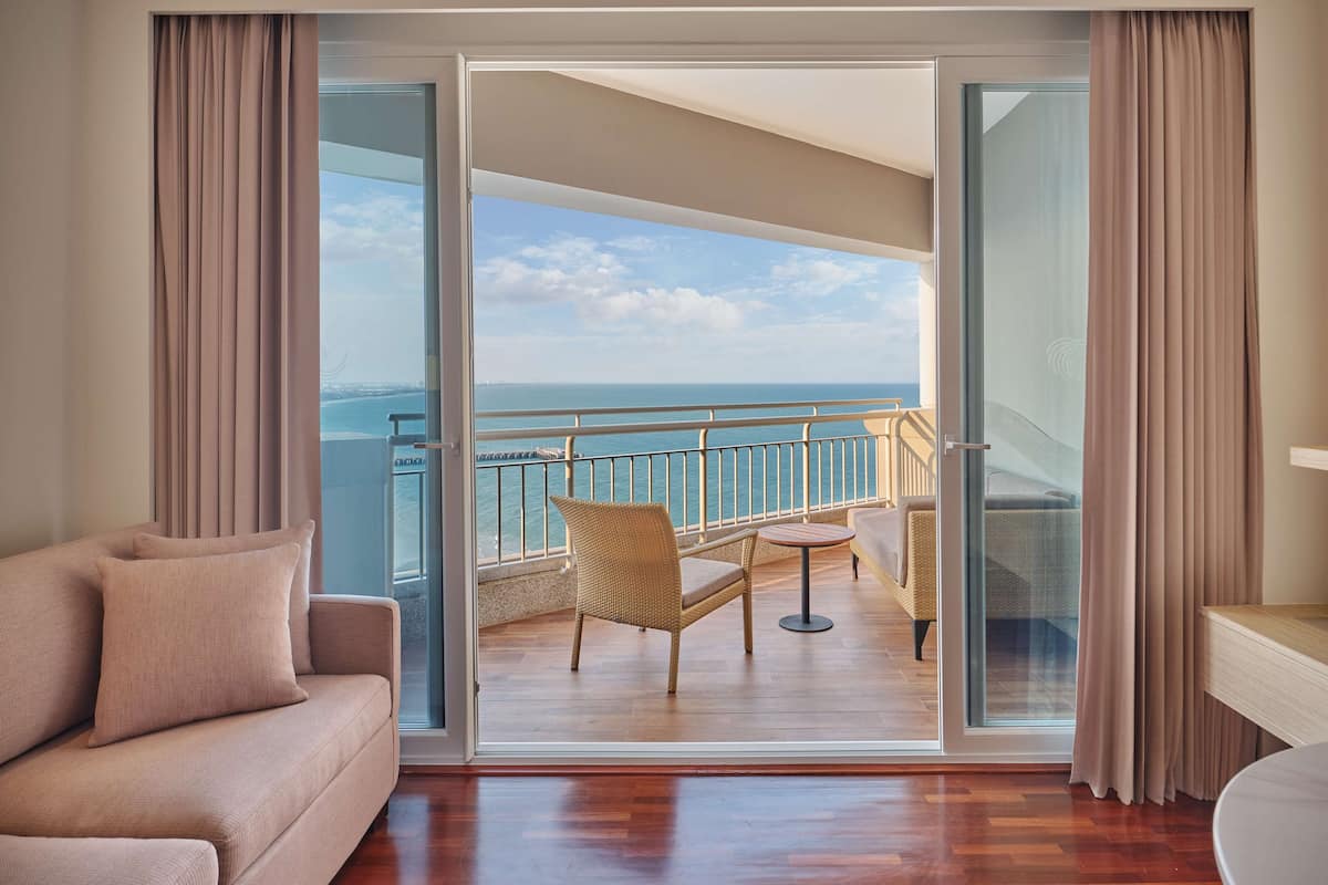 Een balkon met uitzicht op zee, een bank en een kleine tafel.