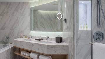 A modern bathroom with a marble vanity, a large mirror, and a glass-enclosed shower area.