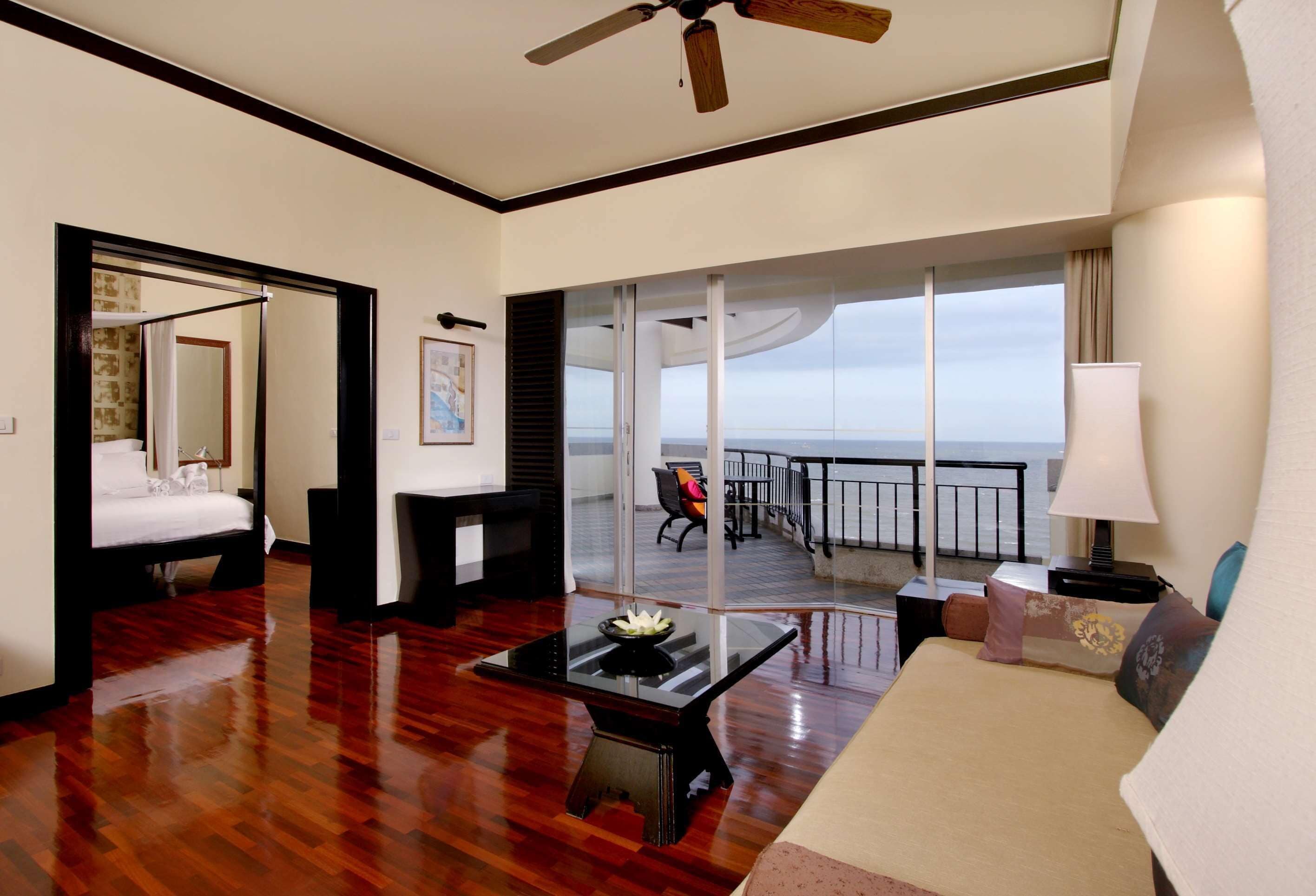 Une chambre d’hôtel comprenant un lit, une table basse, un canapé, un balcon avec vue sur la mer et un ventilateur de plafond.