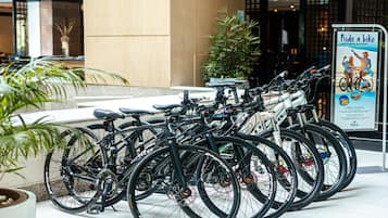 A row of bicycles parked in a hotel lobby with a sign promoting bike rentals.